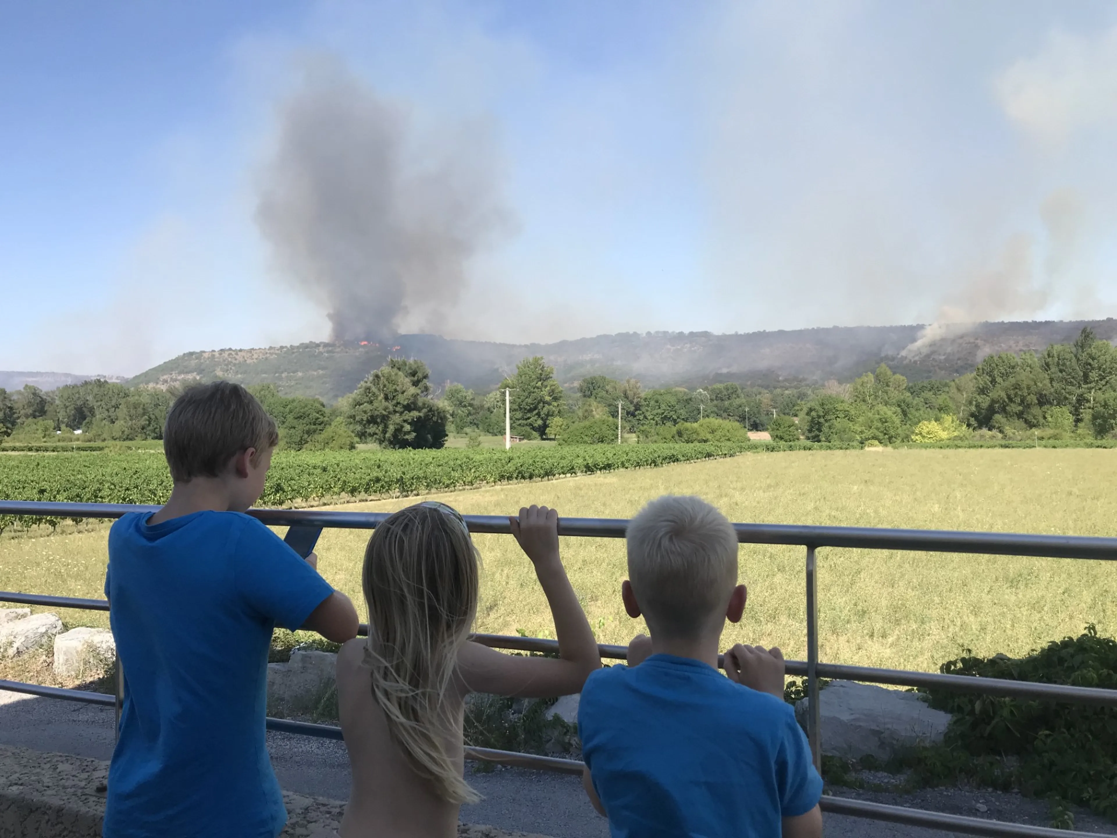 De drie kinderen van Lotte kijken in de verte naar rookwolken die van hun camping afkomen.